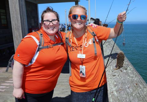 Two tour guides smiling with one fish on pier