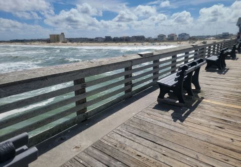 A view of pier handrail, ocean and beach