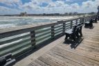 A view of pier handrail, ocean and beach